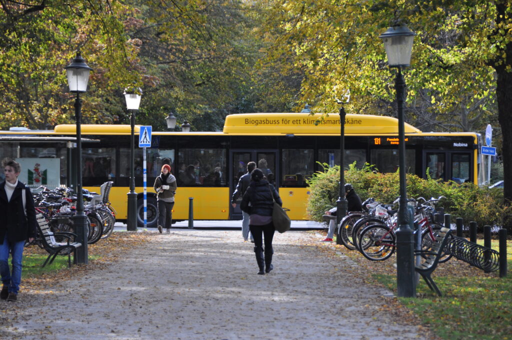 Människor på gångväg och en gul buss.