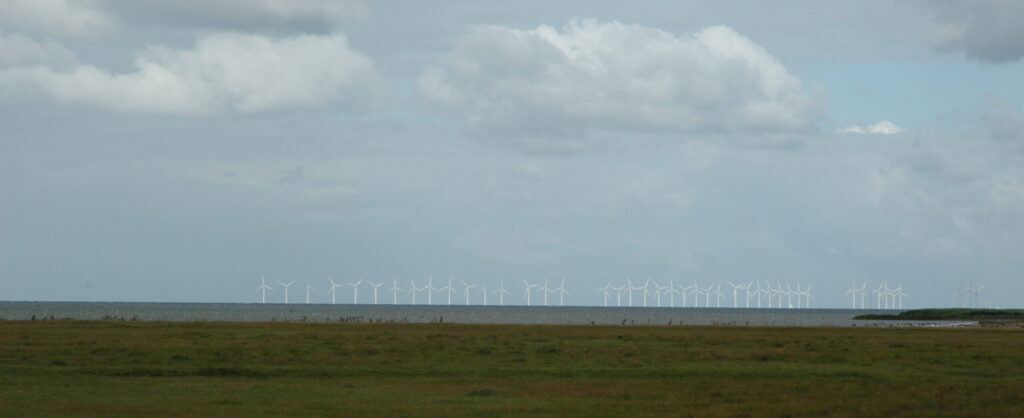 Rad av vindkraftverk vid kusten.