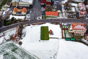 Grön fotbollsplan omgiven av mark täckt med snö