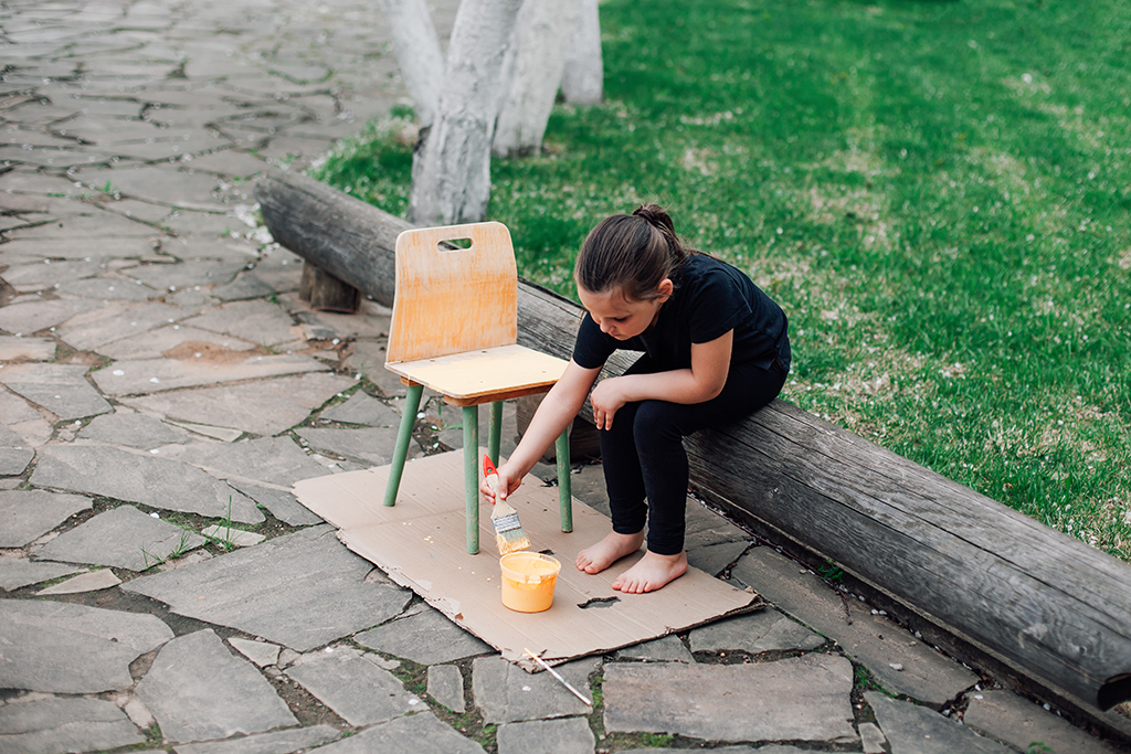 Ett barn målar om en stol.